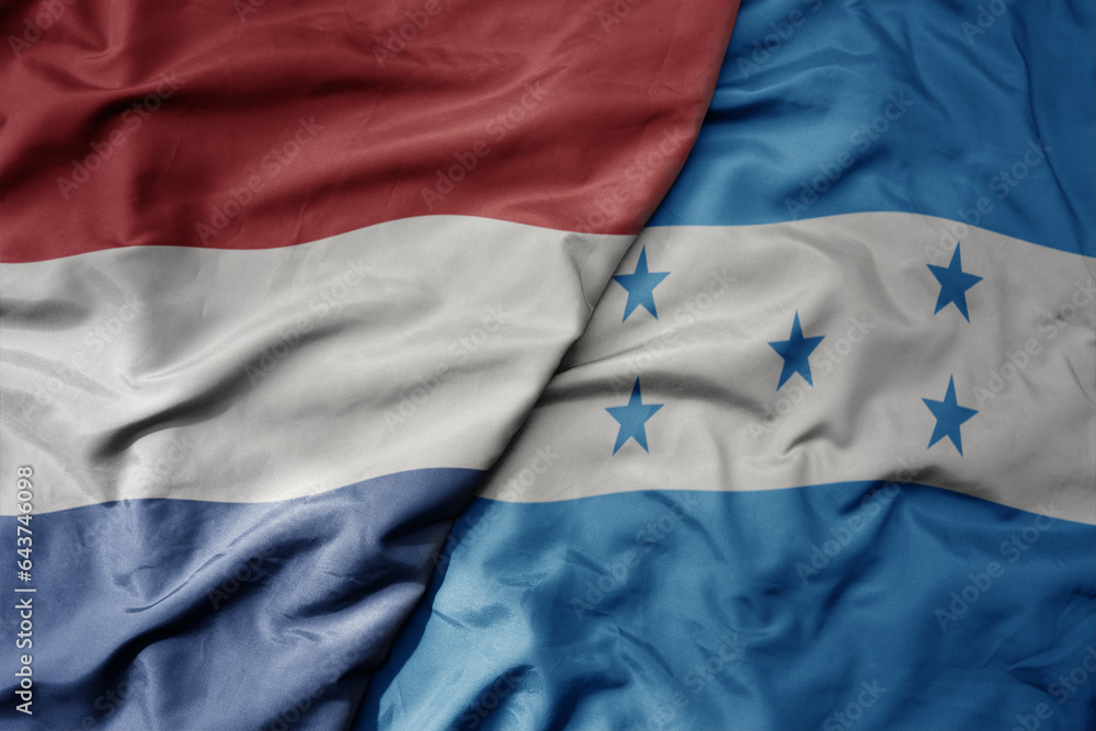 big waving national colorful flag of netherlands and national flag of honduras . big waving national colorful flag of netherlands and national flag of honduras .