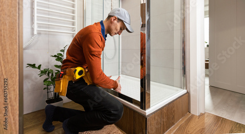 Professional handyman working in shower booth indoors