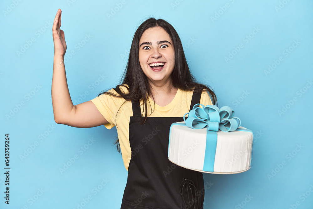Woman with tart in kitchen on blue receiving a pleasant surprise, excited and raising hands. Woman with tart in kitchen on blue receiving a pleasant surprise, excited and raising hands.