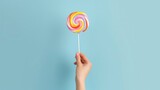 Hand holding yummy candy lollipop on plain background