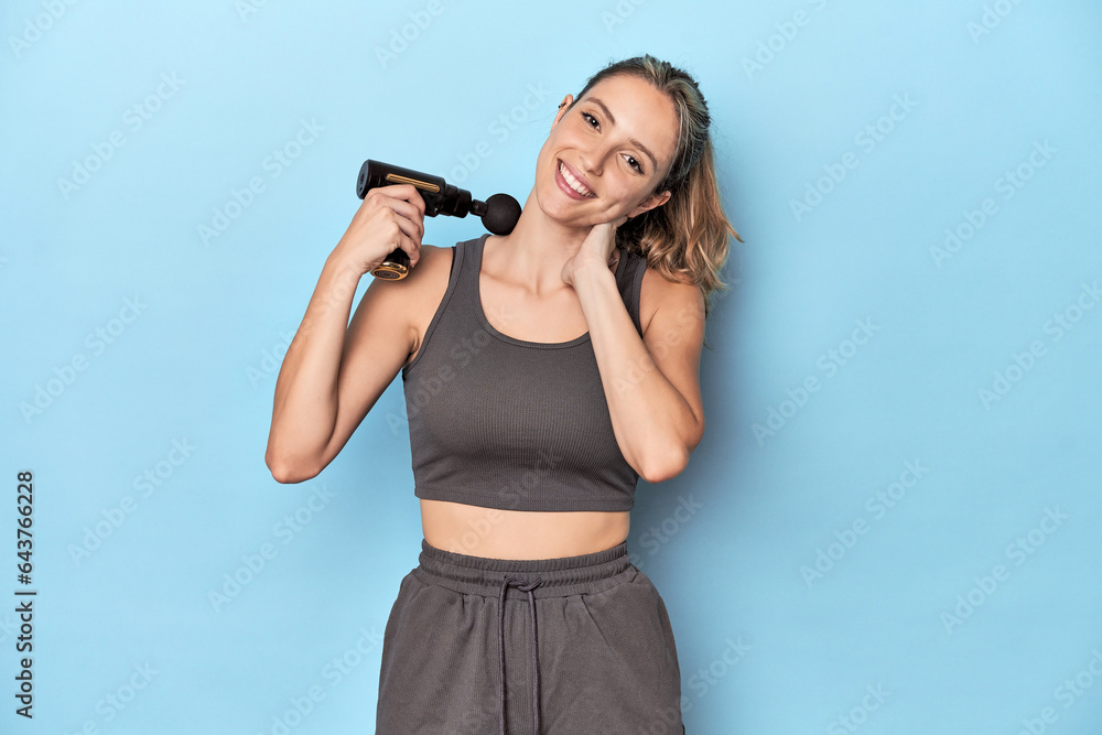Athlete using neck massager in blue studio Athlete using neck massager in blue studio