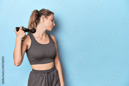 Athlete using neck massager in blue studio