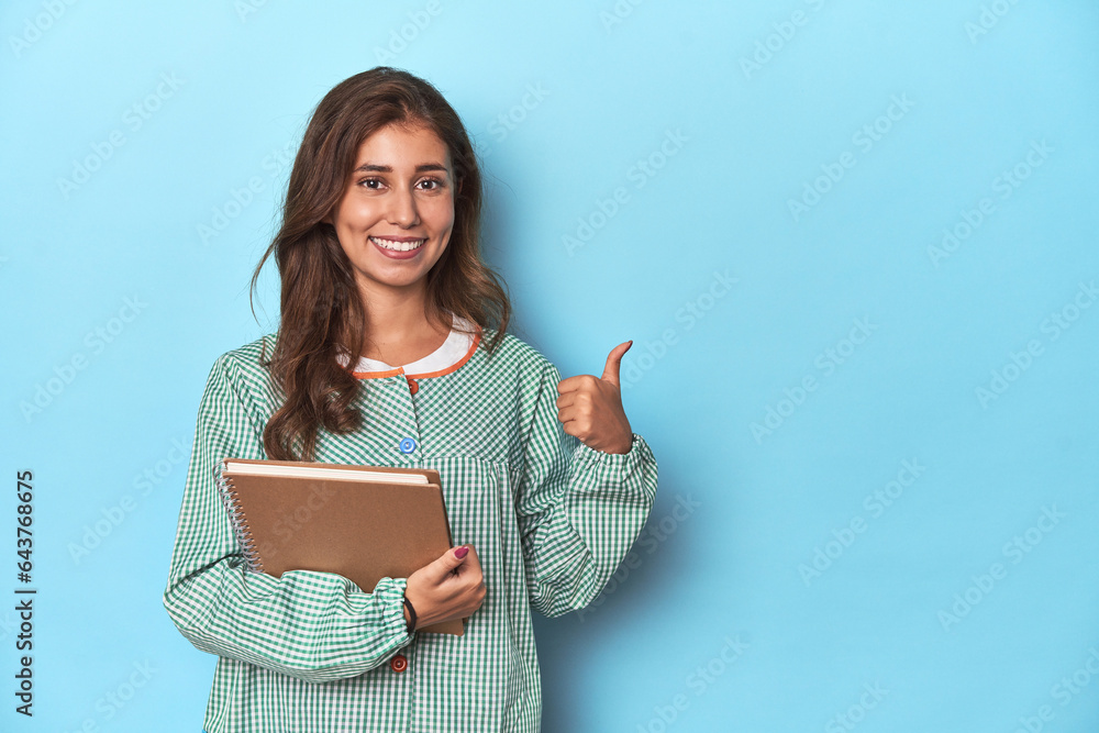 Young teacher holding notebooks, imparting knowledge smiling and raising thumb up Young teacher holding notebooks, imparting knowledge smiling and raising thumb up