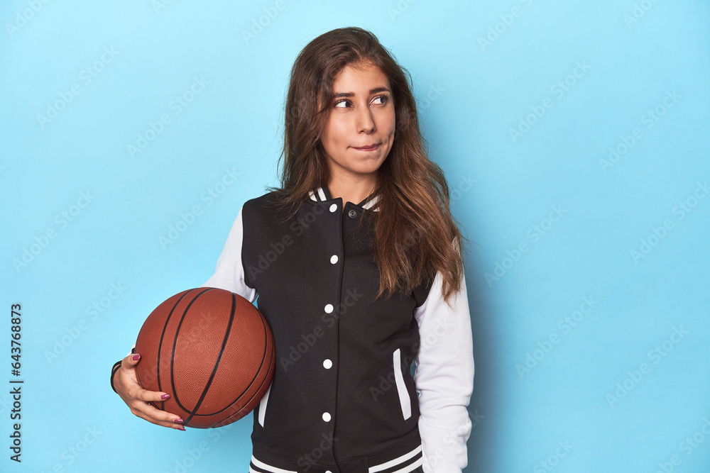 Stylish teen with basketball, embracing sports fashion confused, feels doubtful and unsure. Stylish teen with basketball, embracing sports fashion confused, feels doubtful and unsure.