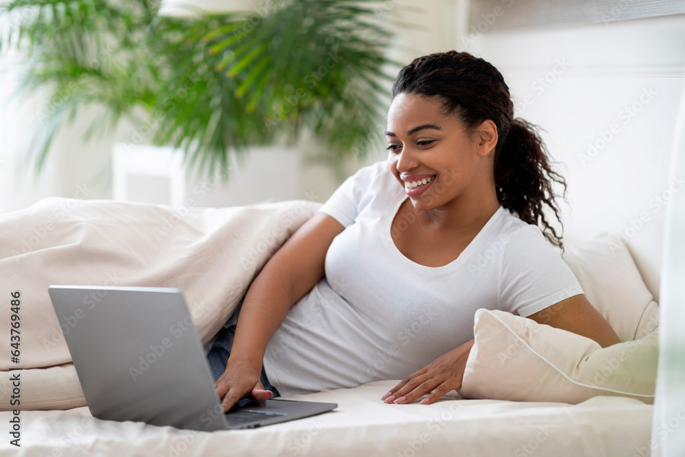 Domestic Leisure. Beautiful Young Black Woman Using Laptop While Lying In Bed Domestic Leisure. Beautiful Young Black Woman Using Laptop While Lying In Bed