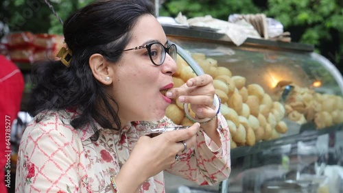 Happy Indian woman having North Indian subcontinent popular street food. Hand cracking panipuri. Street food. Appetizer.