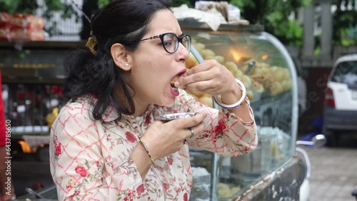 Happy Indian woman having North Indian subcontinent popular street food. Hand cracking panipuri. Street food. Appetizer.