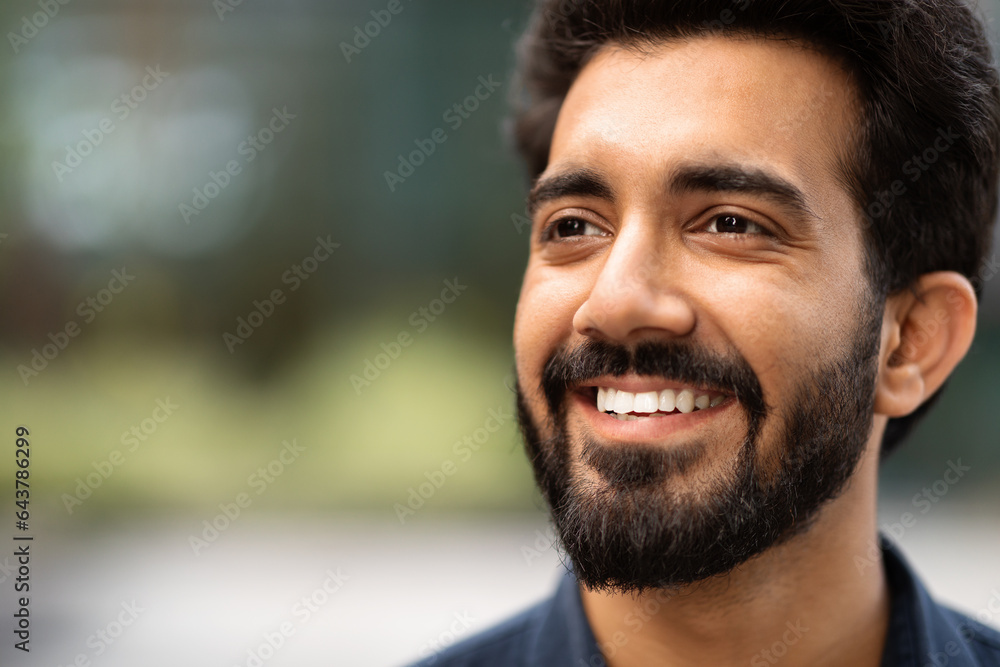 Fototapeta premium Closeup of cheerful handsome indian guy looking at copy space