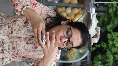 Happy Indian woman having North Indian subcontinent popular street food. Hand cracking panipuri. Street food. Appetizer.