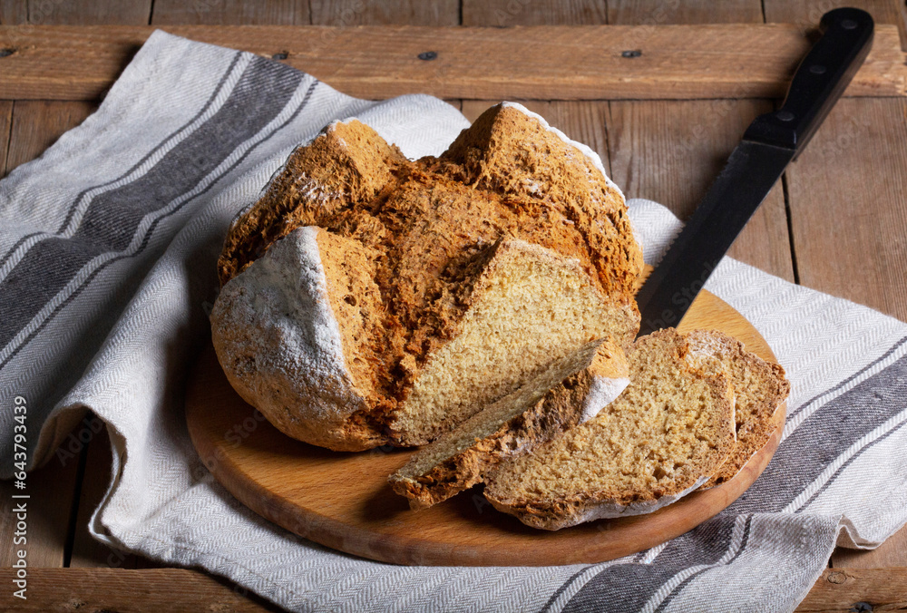 Traditional Irish soda bread made from whole grain and rye flour on a wooden table. Rustic style.