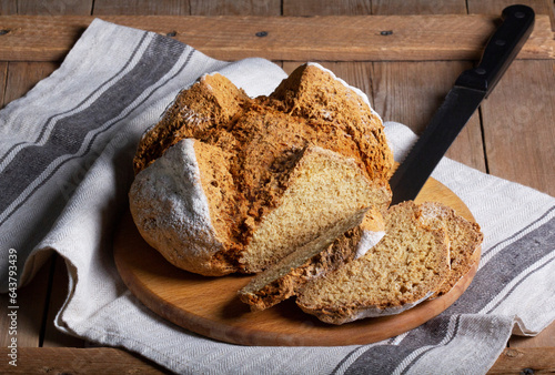 Traditional Irish soda bread made from whole grain and rye flour on a wooden table. Rustic style.