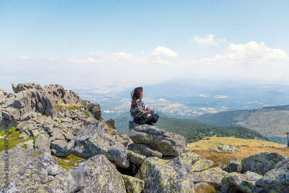 Woman sitting high in the  summer mountain with stunning view 