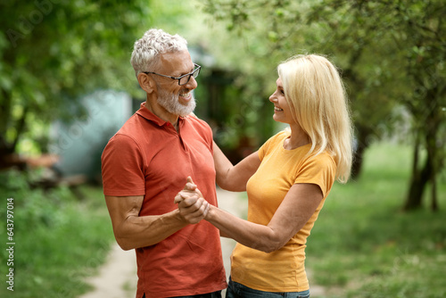 Romantic Senior Spouses Dancing Together Outdoors In Summer Garden