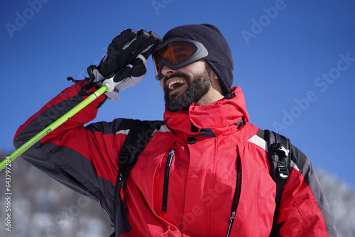 Close-up photo of satisfied young man wearing ski equipment. Happy cheerful man looking into distance while skiing in the mountains.