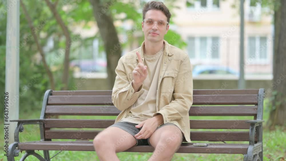 Casual Young Man in Denial while Sititng Outdoor Casual Young Man in Denial while Sititng Outdoor