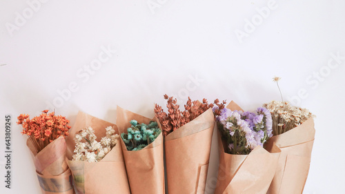 Fotografia Flowers in bunches, herbs, dried flowers in kraft packaging on white background, top view, space for text