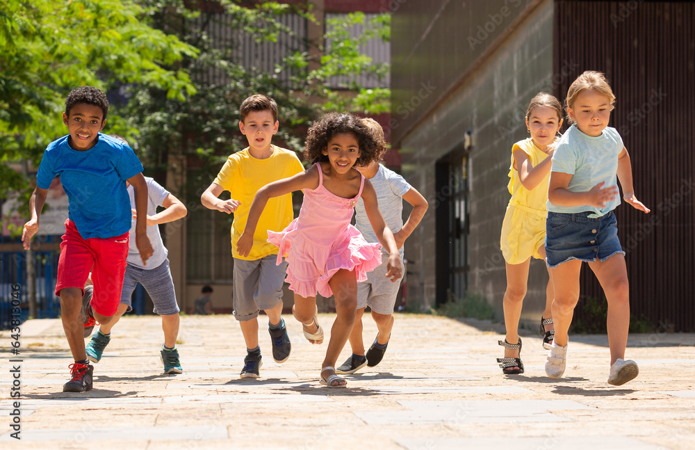 Obraz premium Team of positive kids running in race in the street and laughing outdoors