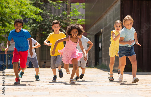 Team of positive kids running in race in the street and laughing outdoors