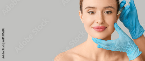 Young woman receiving filler injection in her face against grey background with space for text