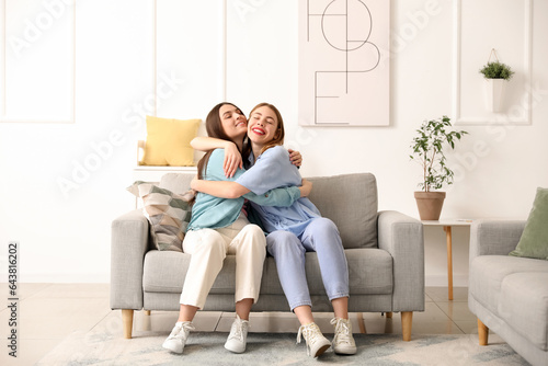 Female friends hugging on sofa at home