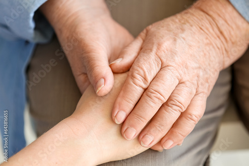 Female caregiver with senior woman holding hands, closeup