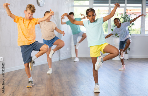 Positive cheerful smiling children studying modern style dance in class indoors