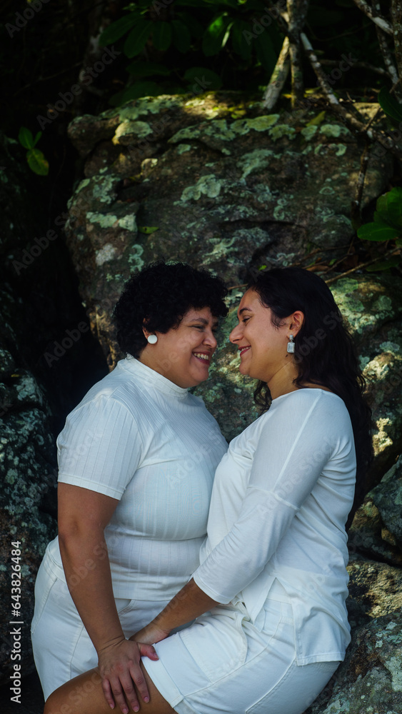 couple of lesbian women on the beach, dressed in white, lgbtqia+ representation, love between women