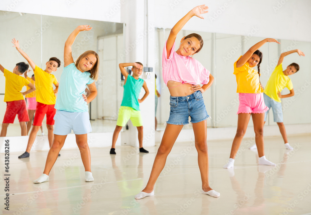 Fototapeta premium Smiling girls and boys doing dance workout during group class in fitness center