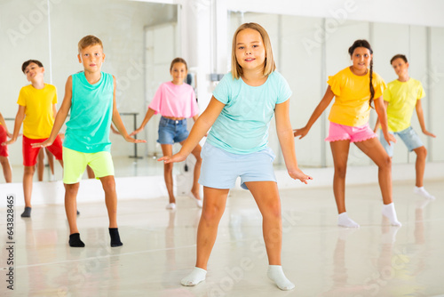 Young girls and boys performing dance in studio during rehearsal.