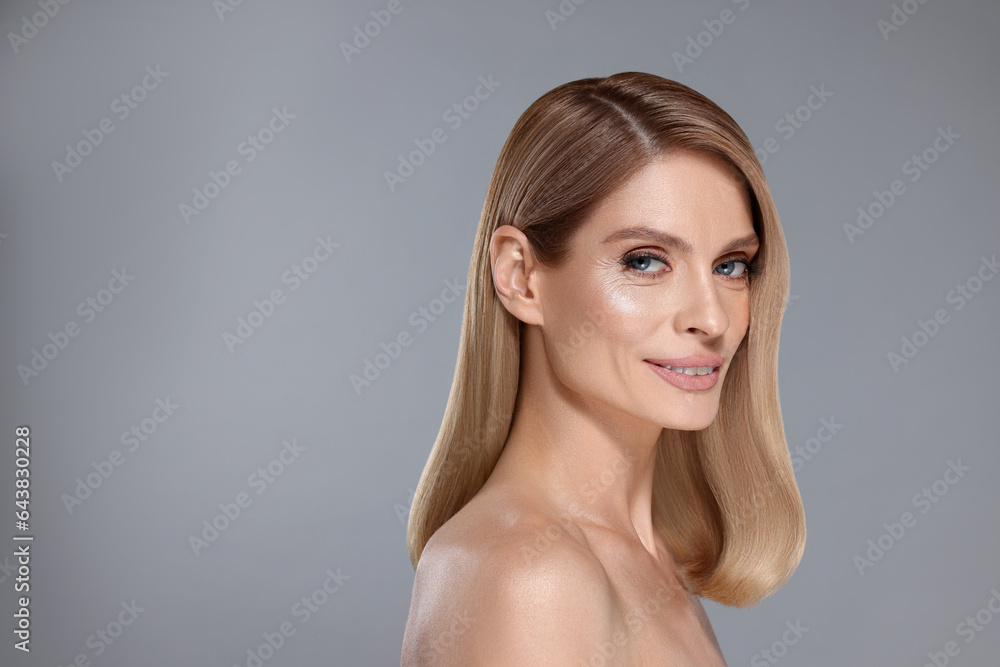 Portrait of attractive woman with blonde hair on grey background, space for text