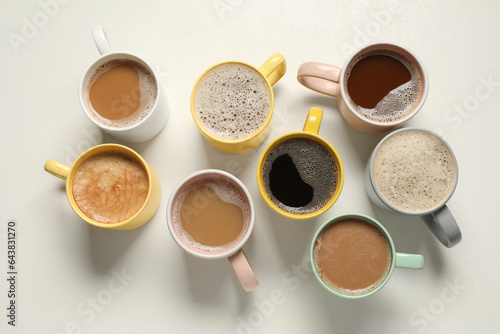 Many cups with different aromatic coffee on white table, flat lay