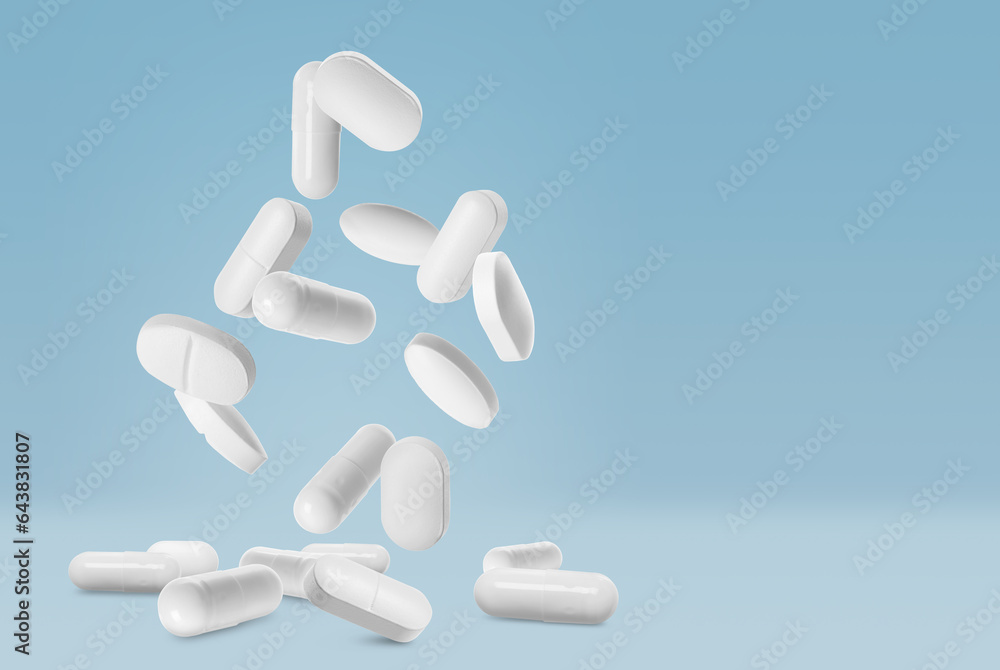 Many different pills falling on light blue background, space for text