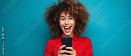 Generative AI : Excited trendy female with hand on cheek smiling and reading great news on smartphone against red background photo