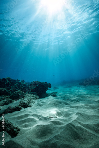 Foto Sun rays penetrating the oceans surface and shining light on a mason jar resting