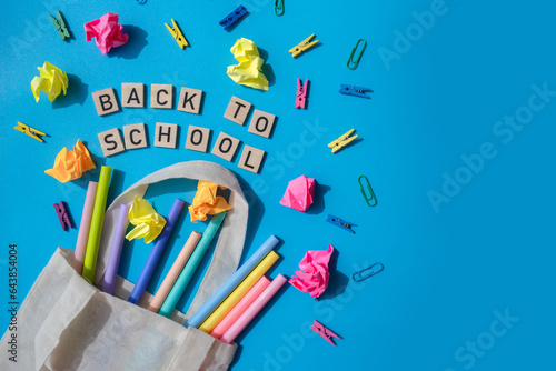 BACK TO SCHOOL message inscription text on wooden blocks on creative colorful blue background with stationery supplies around. Copy space Educational greeting announcement for students and teacher