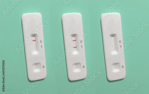 Set of three rapid antigen tests (RAT). The tests are showing a negative and a positive result. One is unused. There are no markings on the test. Rapid antigen detection test (RADT)