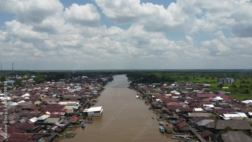 Aerial view of the City on the river's banks with the activity of boats speeding over the river. Pangkalan Bun, central kalimantan, Indonesia - 25 August 2023 Aerial view of the City on the river's banks with the activity of boats speeding over the river. Pangkalan Bun, central kalimantan, Indonesia - 25 August 2023