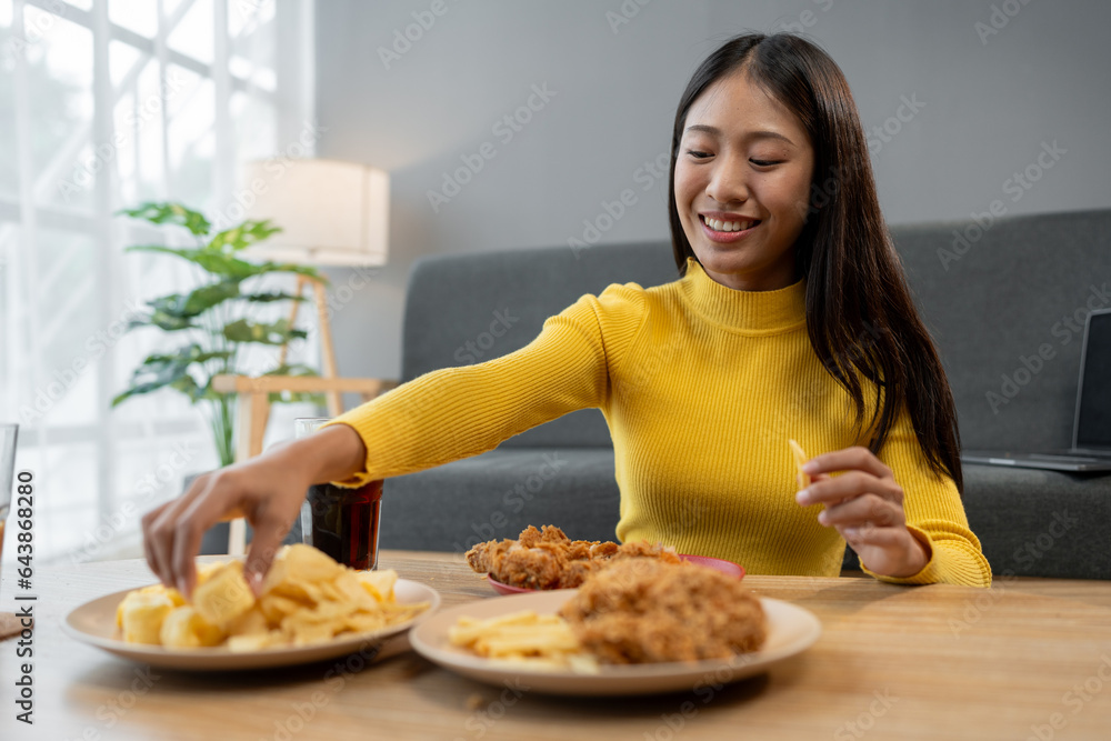Young Asian woman enjoying a party, relaxing, having fun eating food, snacks, drinking soft drinks happily at living room. Party, weekend, celebration, Christmas, New Year, lifestyle, study, work.