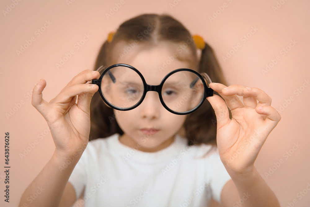 Portrait of an out-of-focus smart preschool girl holding round diopter glasses in front of her in focus. Portrait of an out-of-focus smart preschool girl holding round diopter glasses in front of her in focus.