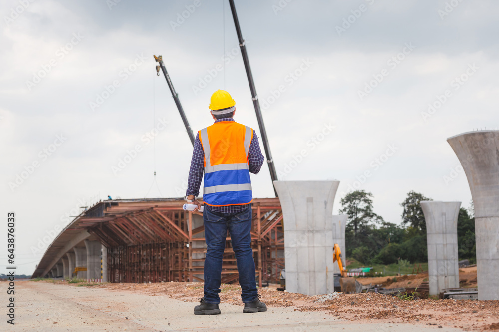 Rear view of Engineer under inspection and checking project at the building site, Foreman worker in hardhat at the infrastructure construction site