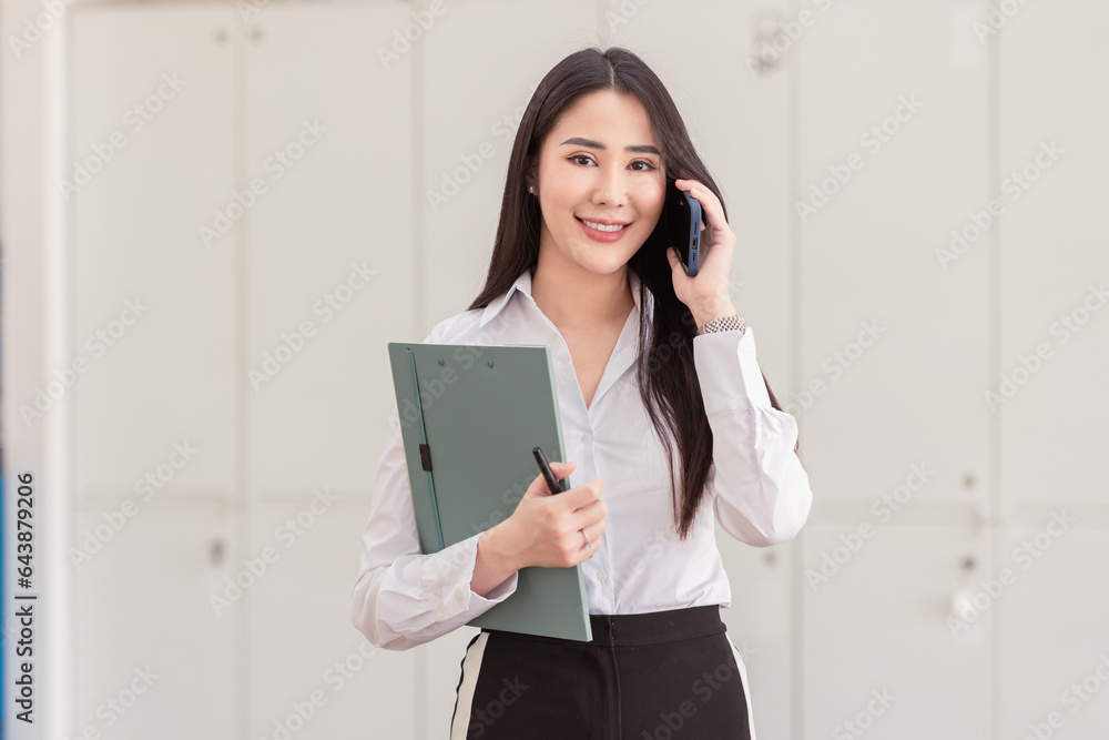 Portrait of young asian woman, company worker in phone smiling and call phone, standing over white background Portrait of young asian woman, company worker in phone smiling and call phone, standing over white background
