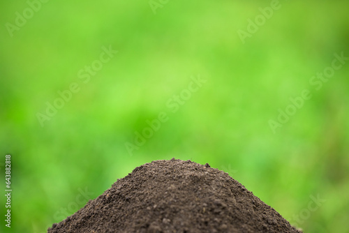 fertile pile of soil with green grass blurred background