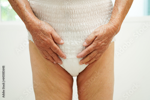 Asian senior woman patient wearing adult incontinence diaper pad in hospital.