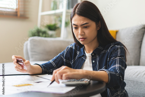 Business financial concept, stressed asian young woman hand checking list statement of credit card  for calculate accounting expense, tax for payment on due deadline, trying to find money to pay debt