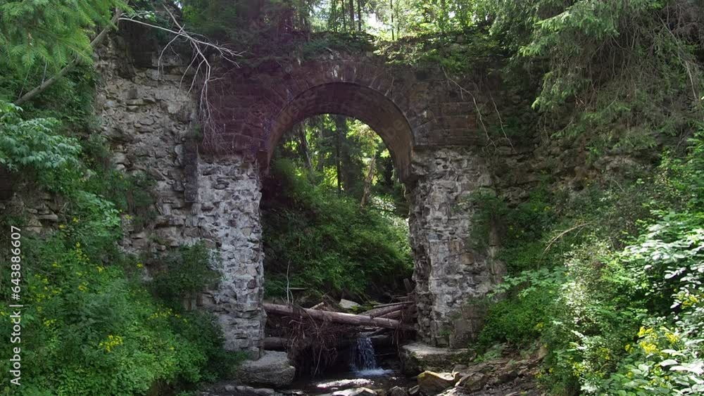 Picturesque ruins of the narrow-gauge viaduct carriage bridge in the village of Vorokhta, Carpathian Mountains, Ukraine. Old stone arched destroyed bridge over small river in a mountain forest. Picturesque ruins of the narrow-gauge viaduct carriage bridge in the village of Vorokhta, Carpathian Mountains, Ukraine. Old stone arched destroyed bridge over small river in a mountain forest.