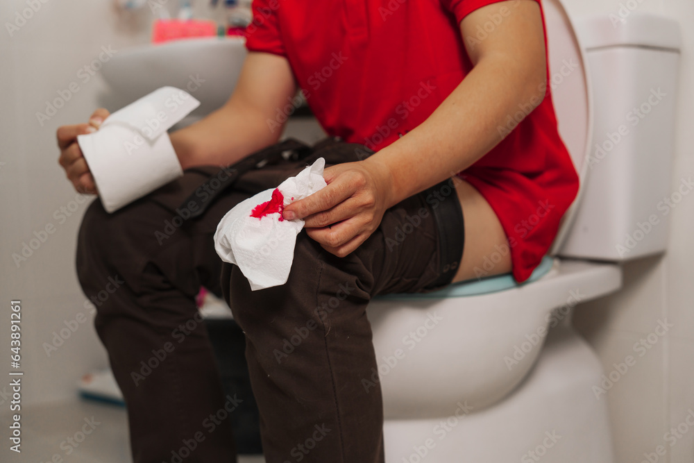 Man using tissue paper in the toilet for relief, health and wellness, hemorrhoids and personal hygiene