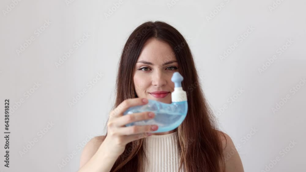 A young woman demonstrates the Neti Pot for treating runny nose and colds. Nasal rinsing, irrigation therapy. A young woman demonstrates the Neti Pot for treating runny nose and colds. Nasal rinsing, irrigation therapy.