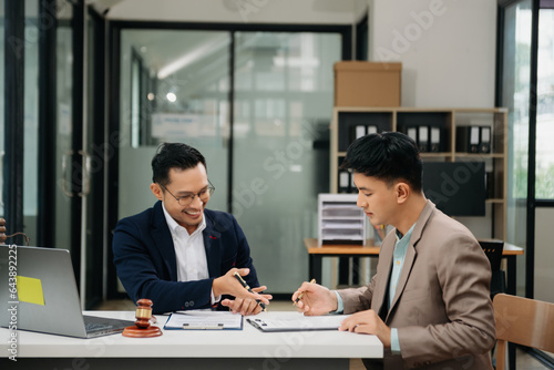 Business and lawyers discussing contract papers with brass scale on desk in office. Law, legal services, advice, justice and law concept ..