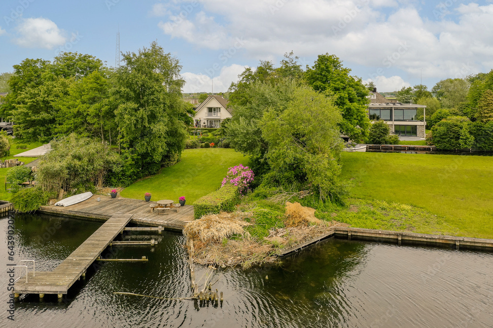 Fototapeta premium a boat dock in the middle of a body of water surrounded by lush green trees and houses on both sides