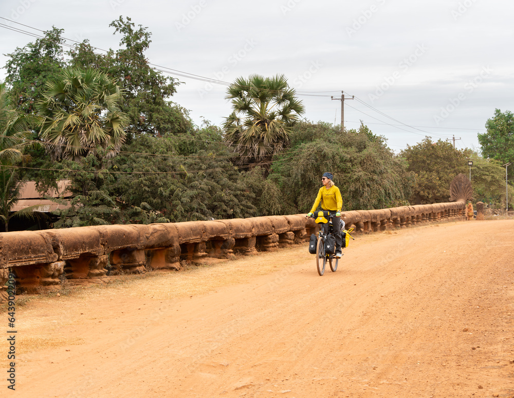 Traveler woman on her bicycle loaded with bags passing through t Traveler woman on her bicycle loaded with bags passing through t
